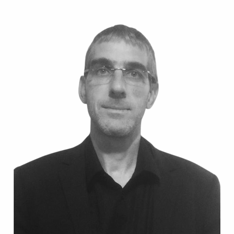 Fid'Equin : Photo en noir et blanc d'un homme qui regarde devant lui, en mode portrait. Il porte des lunettes. Son haut/ tee-shirt est foncé.