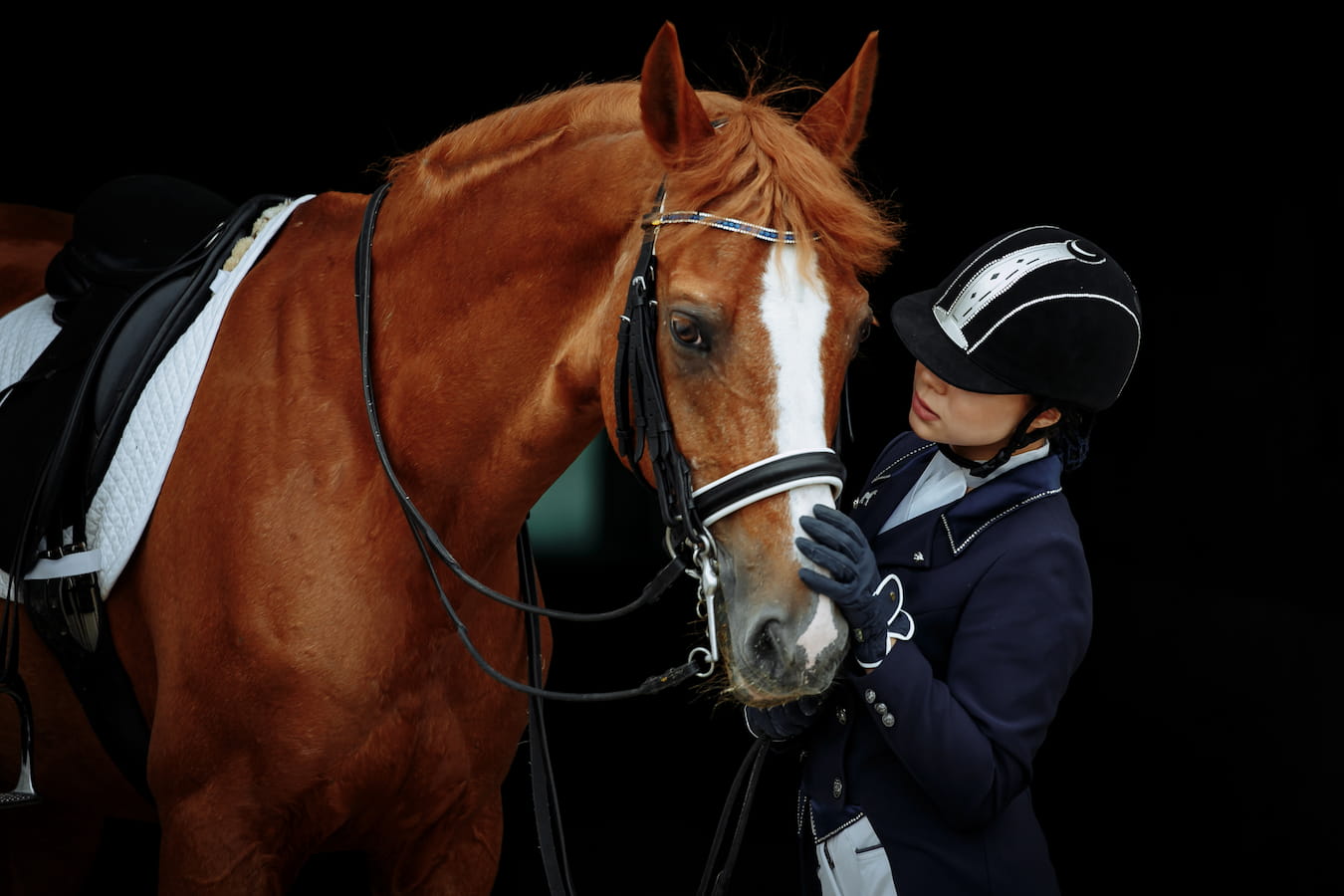 Fid'Equin. Photo avec au centre un cavalier professionnel à côté de son cheval. Le fond est noir.